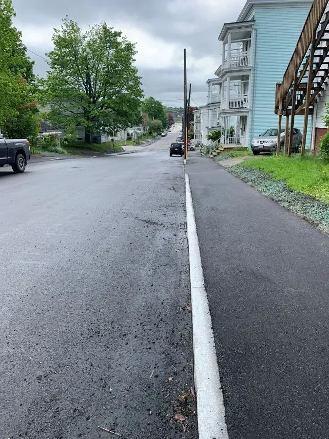 A black truck is parked on the side of the road next to a white line.