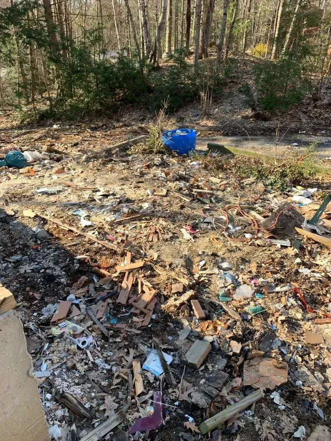 There is a lot of trash on the ground in the woods.