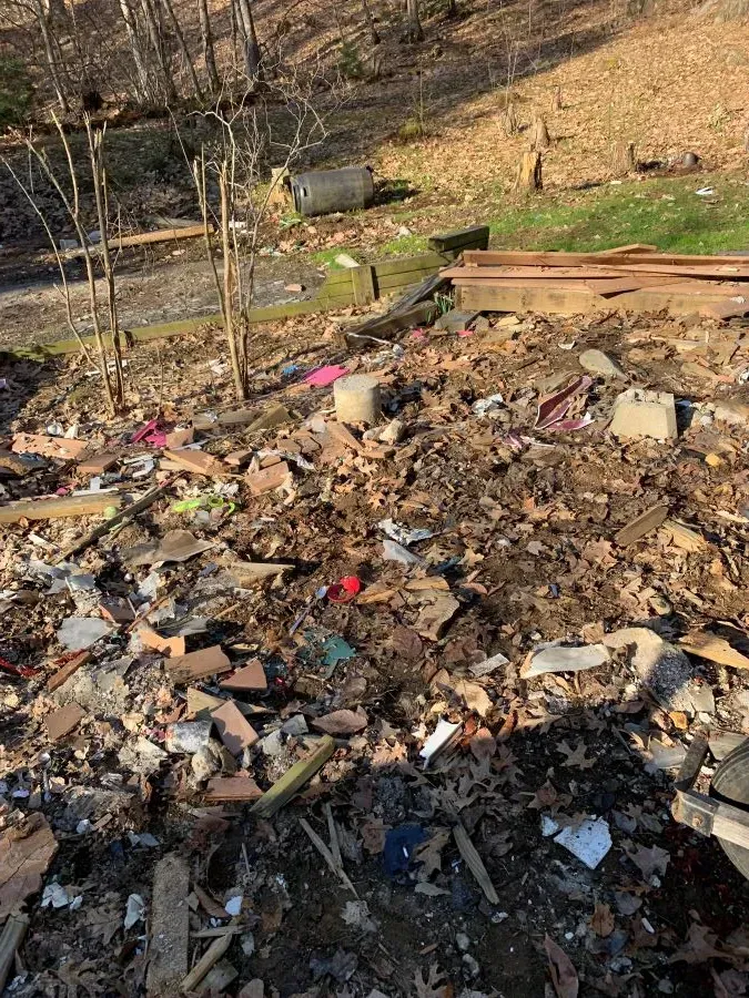 There is a lot of trash on the ground in the woods.