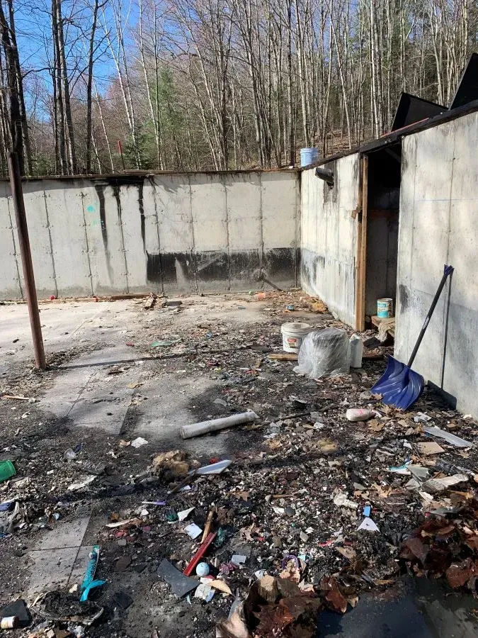 There is a lot of trash in the backyard of a house.