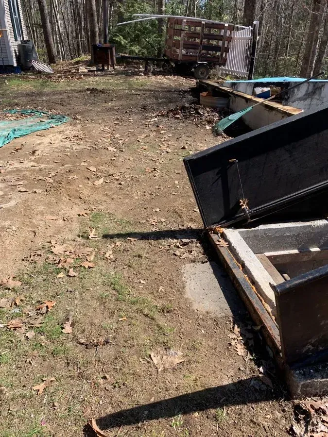 A dumpster is sitting in the middle of a dirt field.
