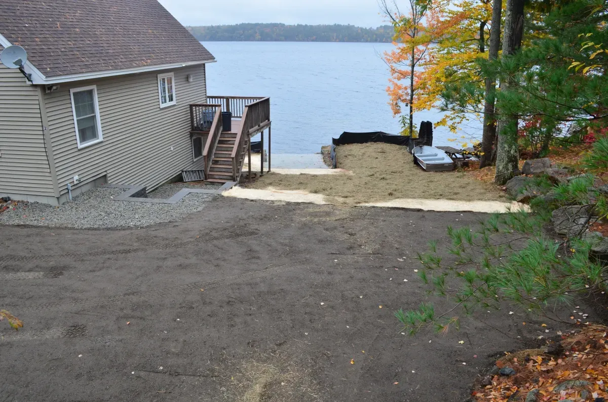 A house with stairs leading up to a deck overlooking a lake