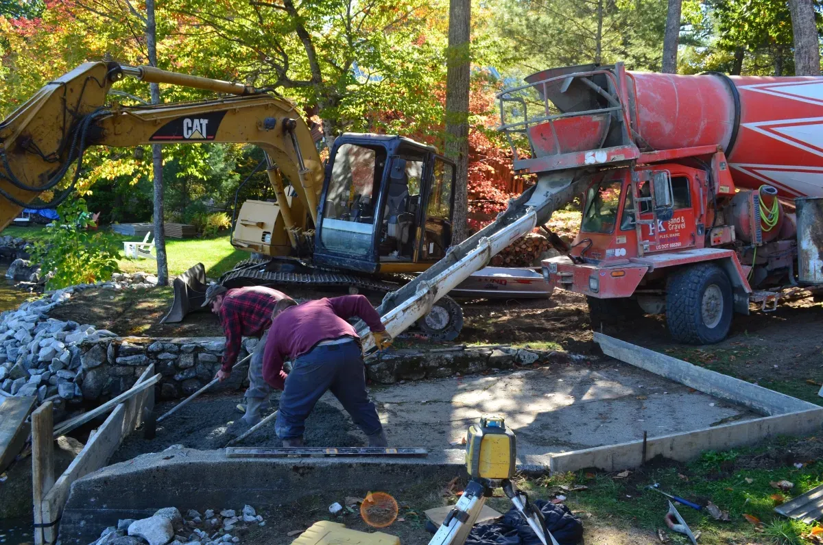 A man is working on a concrete driveway next to a mixer truck.
