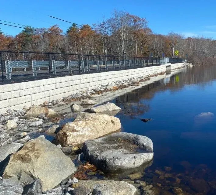 A bridge over a body of water with rocks on the shore