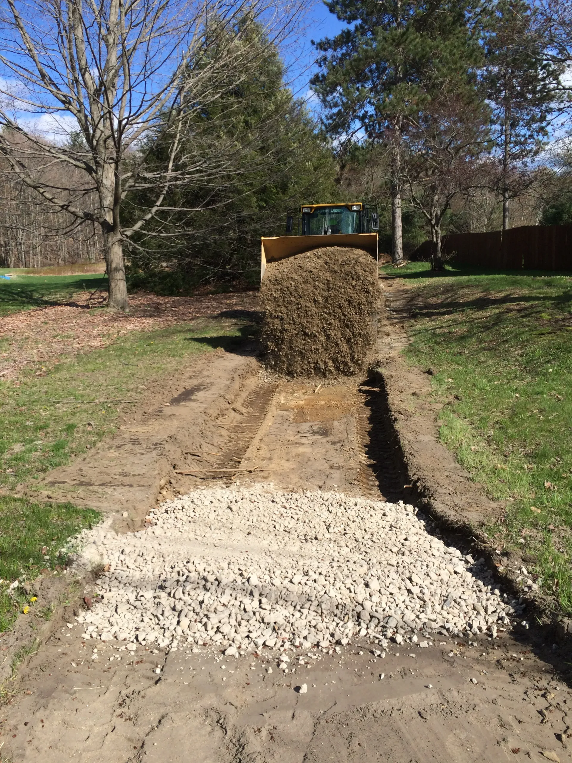 A bulldozer is loading gravel into a driveway.