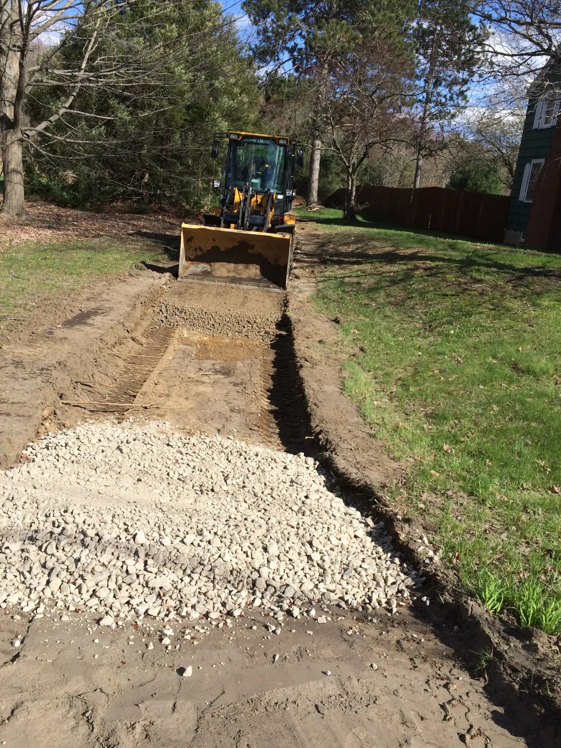 A bulldozer is driving down a dirt road next to a pile of gravel.