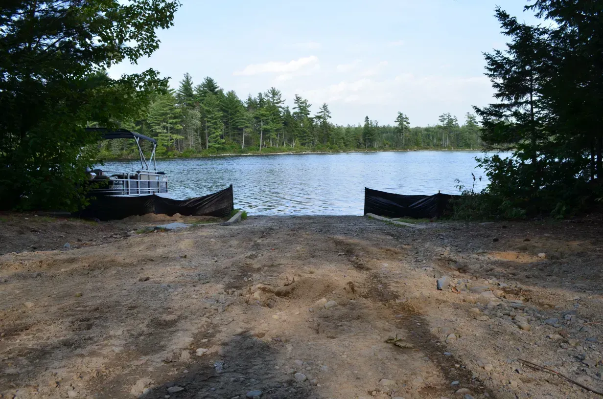 A boat ramp leading to a lake with trees in the background