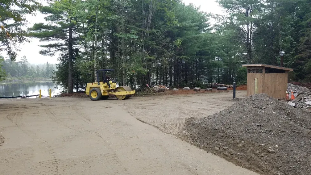 A yellow bulldozer is parked on the side of a dirt road.