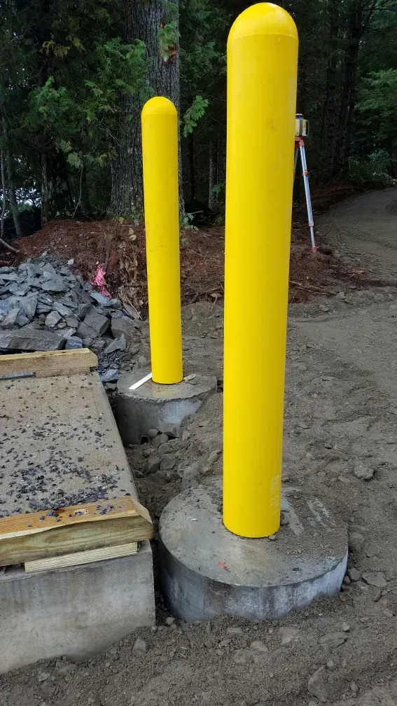 A couple of yellow poles sitting on top of a concrete base.