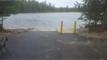 A bicycle is parked on the side of a road next to a dock leading to a lake.