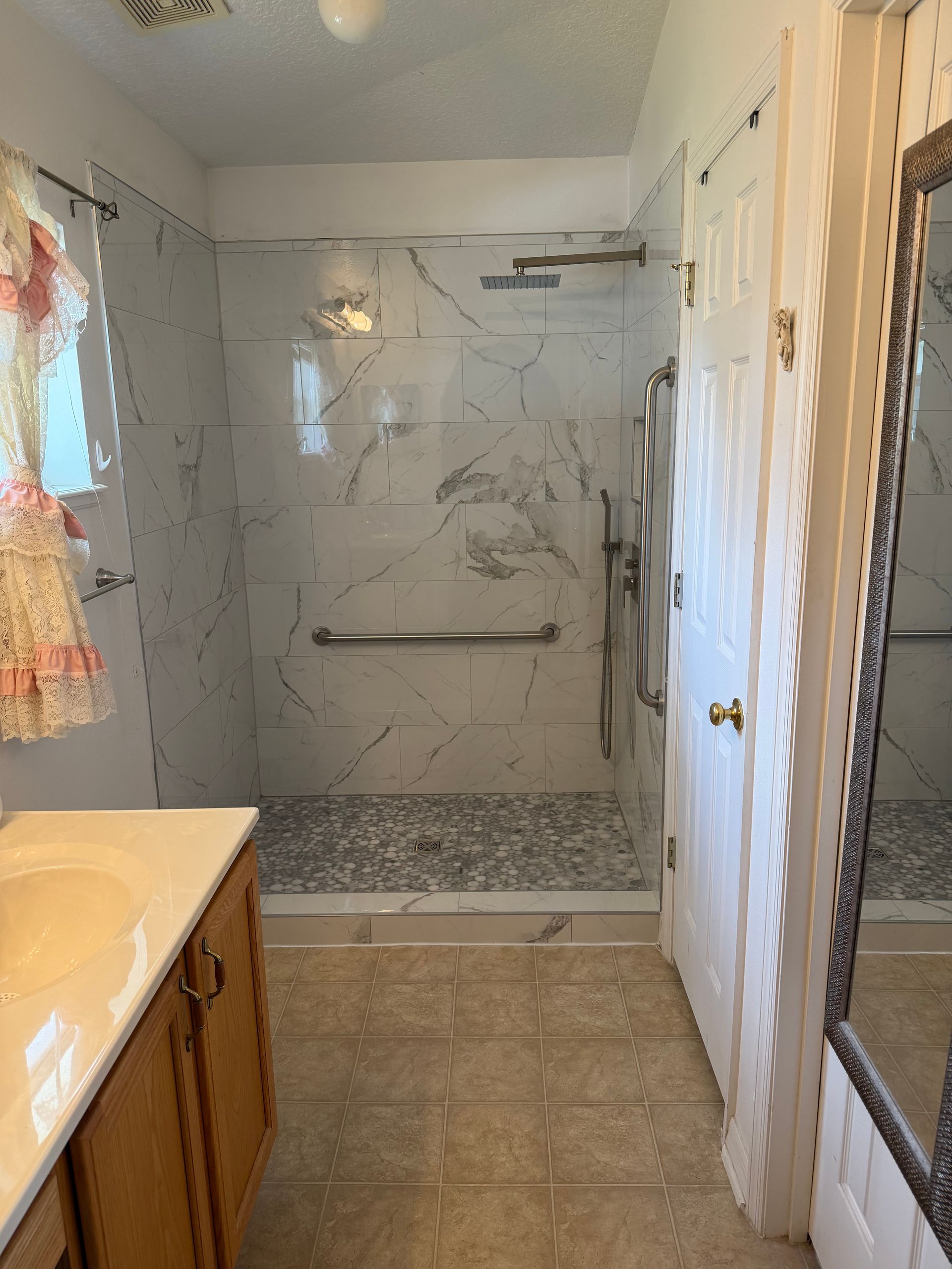 Bathroom with tiled shower, glass door, and vanity sink in a narrow room.