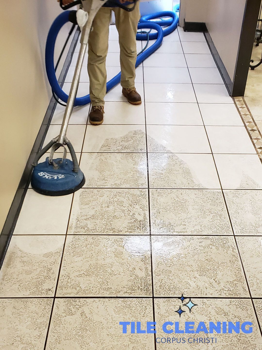 Person using floor buffer to clean a tile floor in a room.