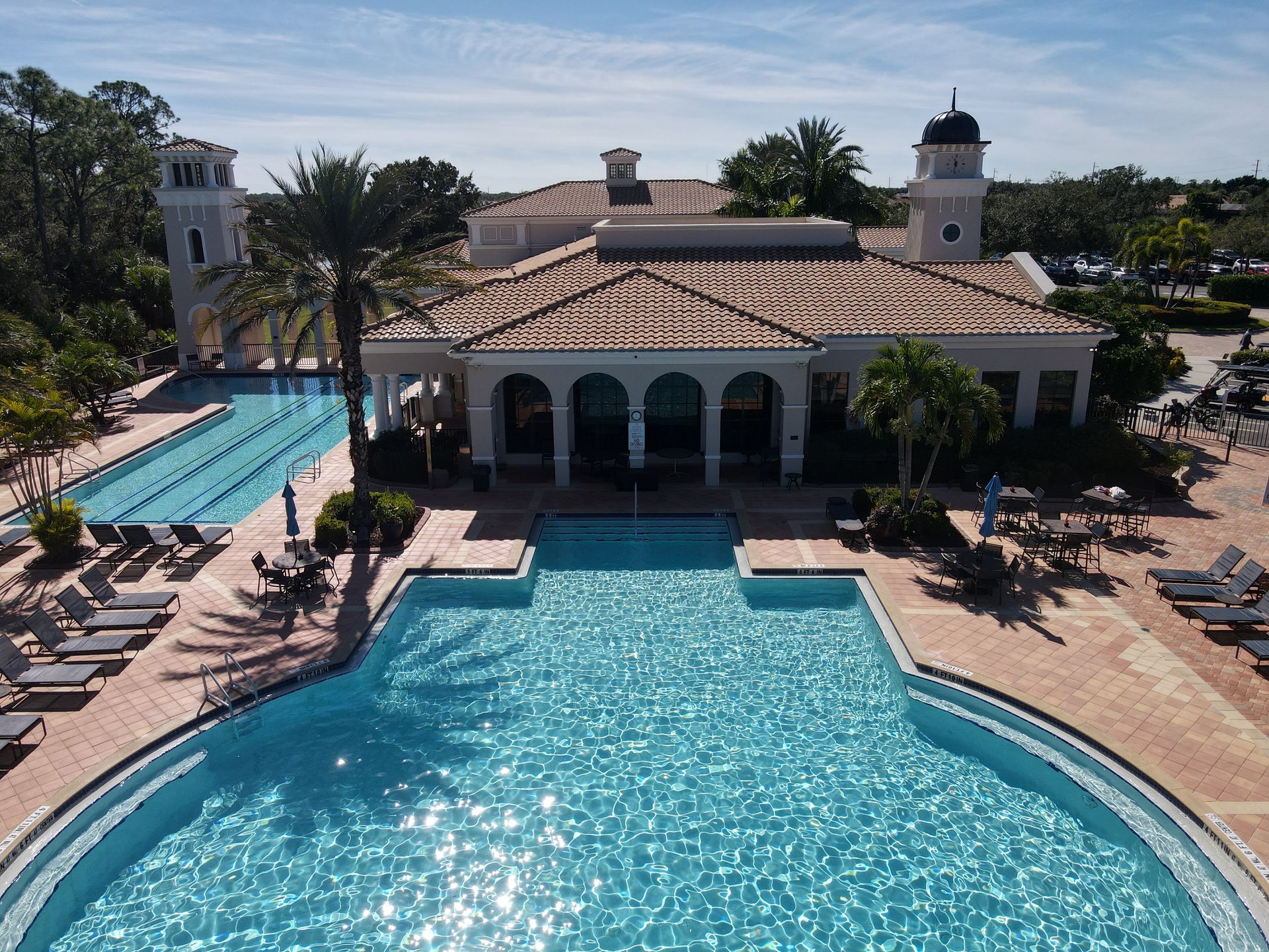 A swimming pool and a building with a tiled roof. Two towers flank the structure.