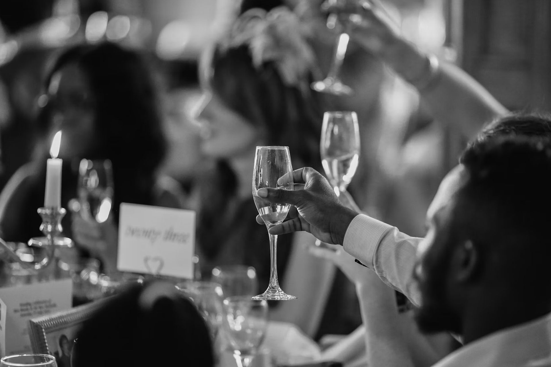 People toasting with champagne glasses at a table, soft focus.
