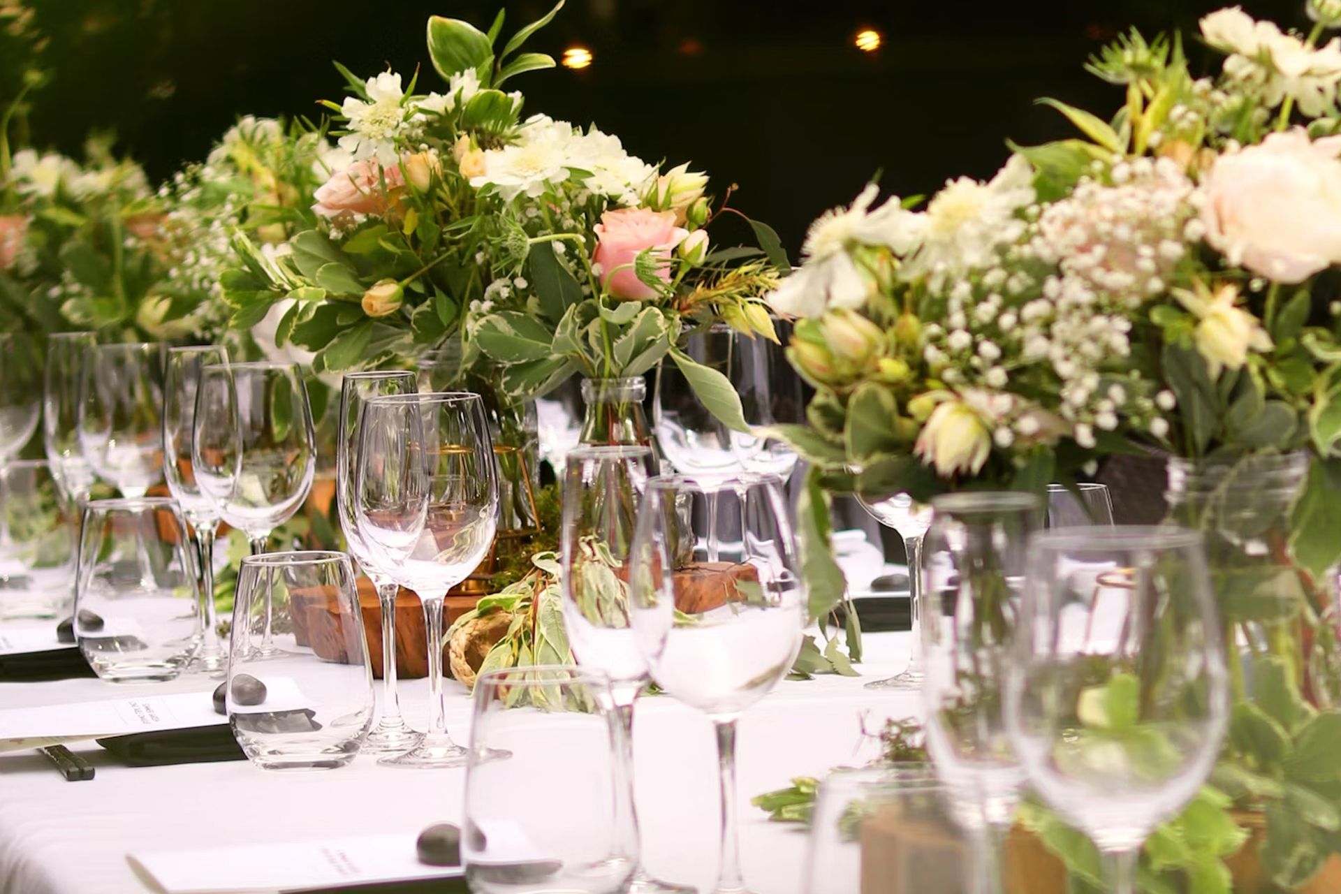 Long table set for a formal event with wine glasses and floral centerpieces.