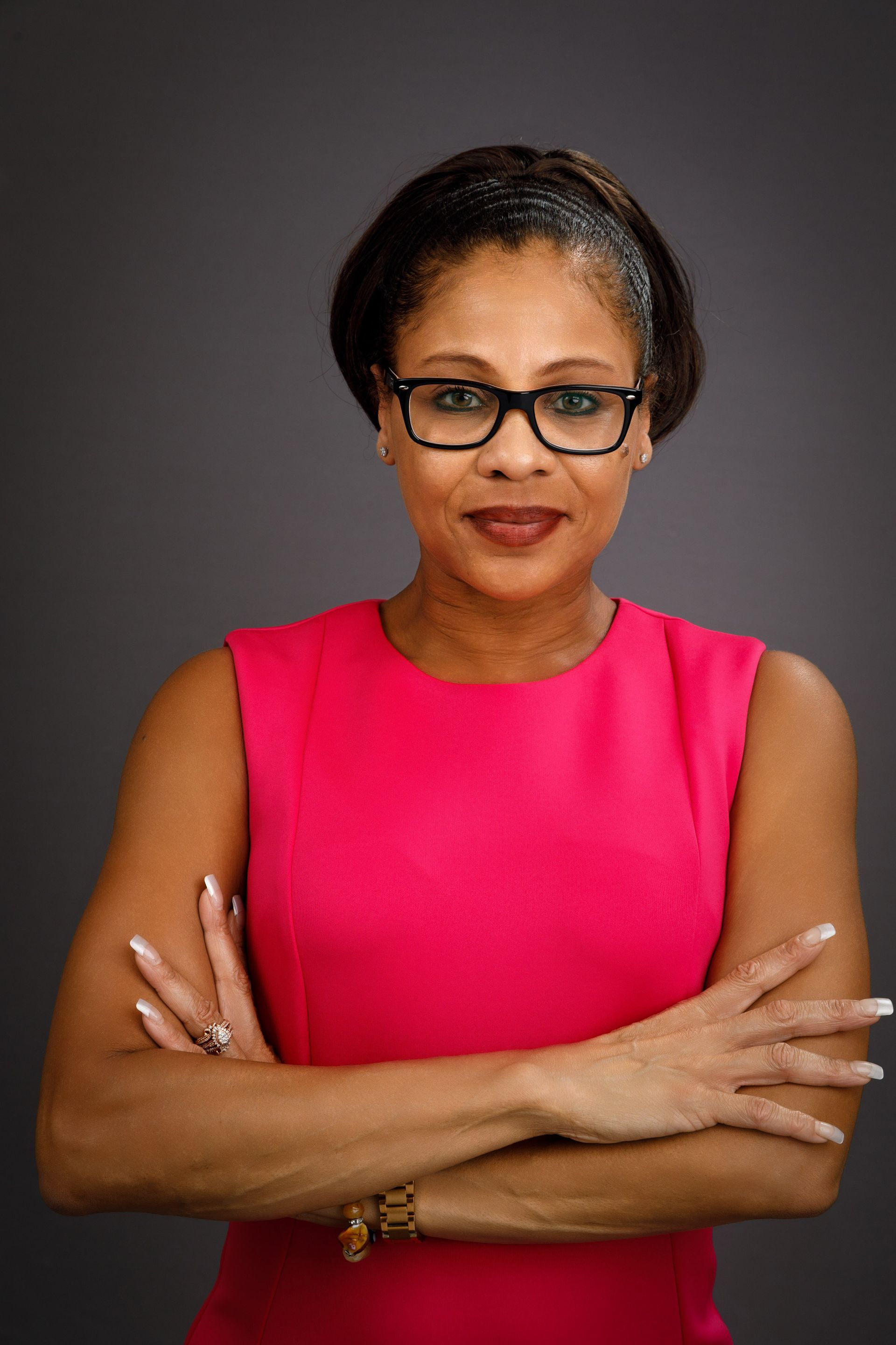 A woman is sitting at a desk with a laptop and a vase of flowers.