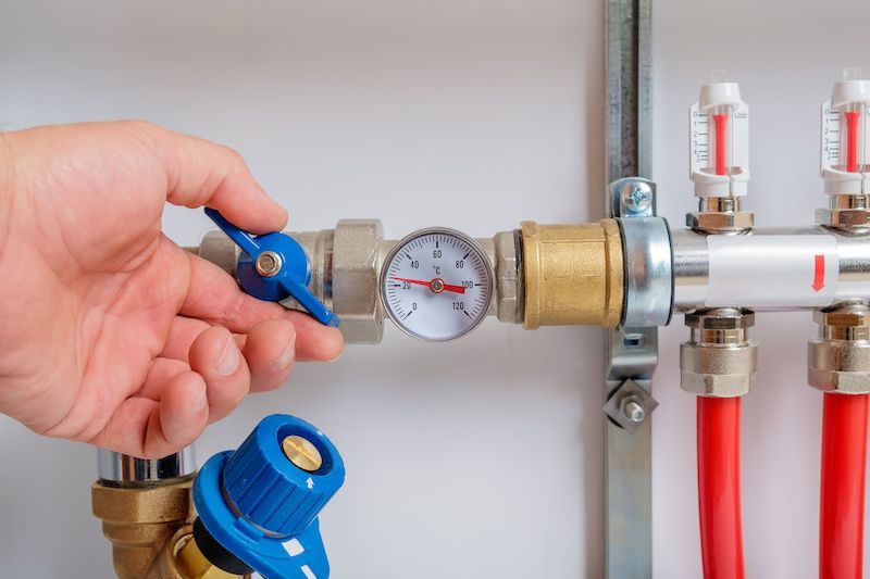 A person is adjusting a valve on a heating system.