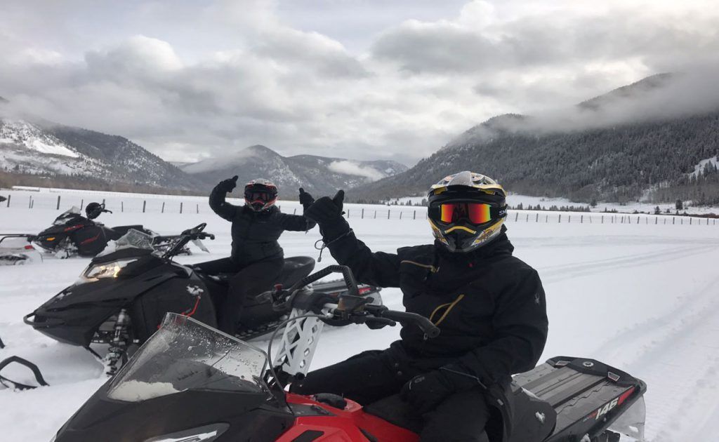 A man is sitting on a snowmobile in the snow.