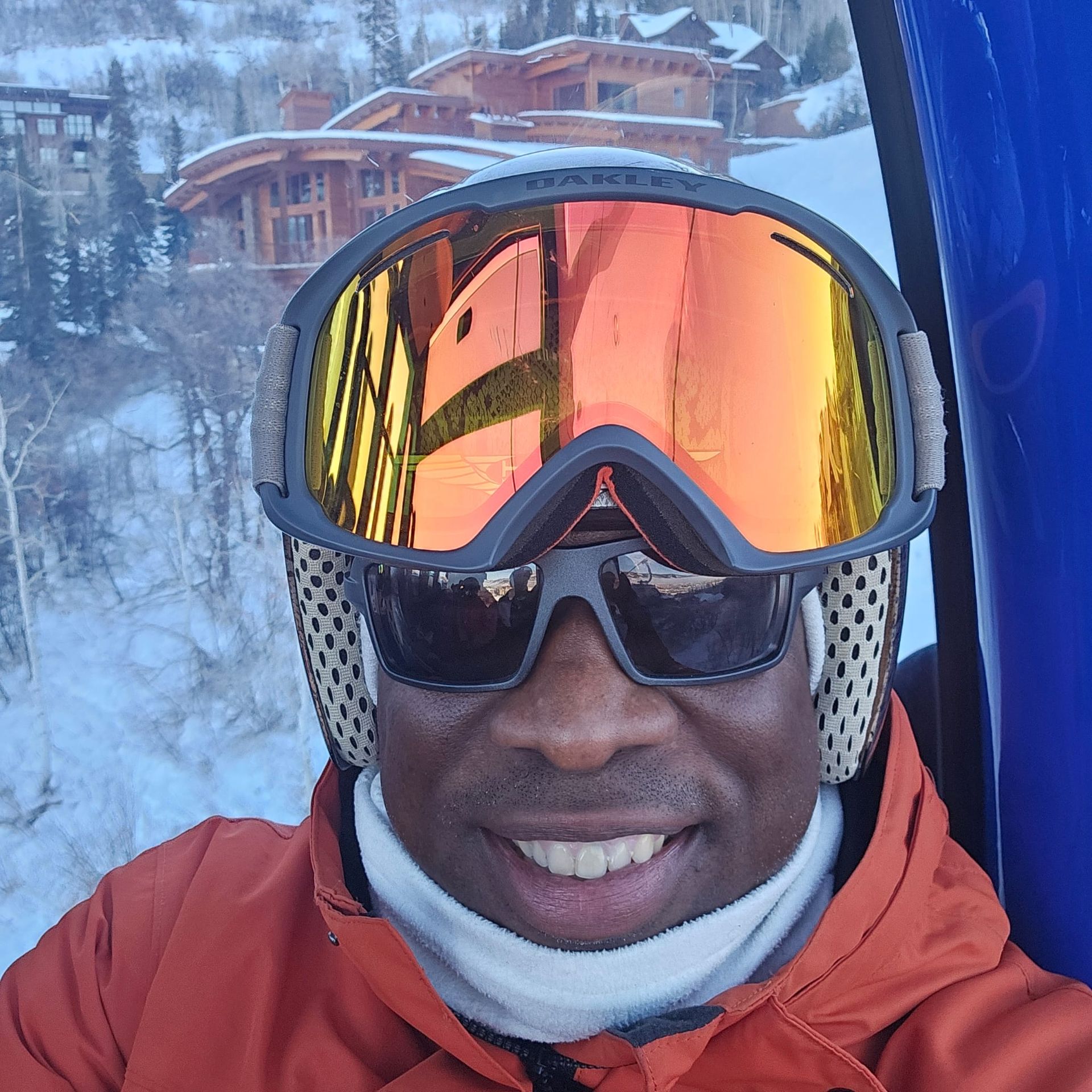 A man wearing sunglasses and goggles is smiling for the camera