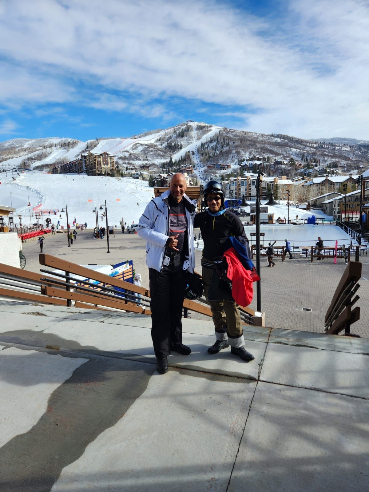 Two men are posing for a picture in front of a snowy mountain.