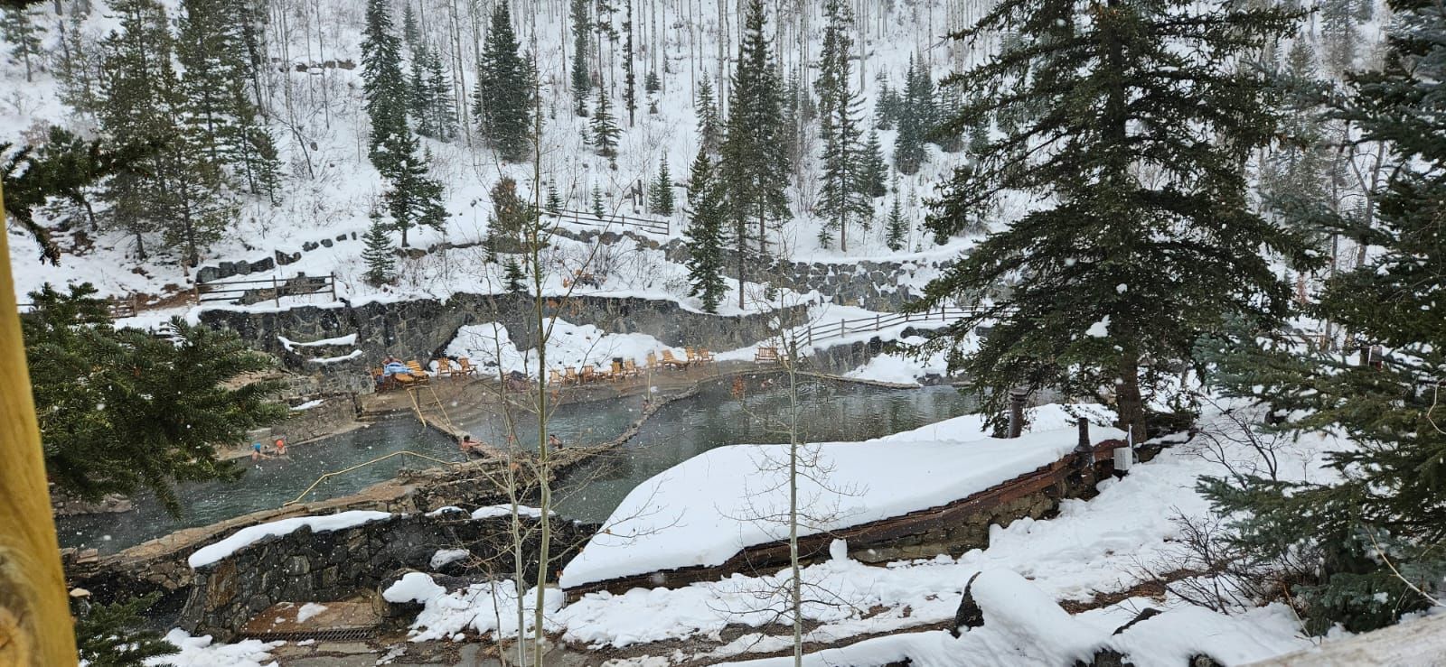 A large body of water surrounded by snow covered trees.