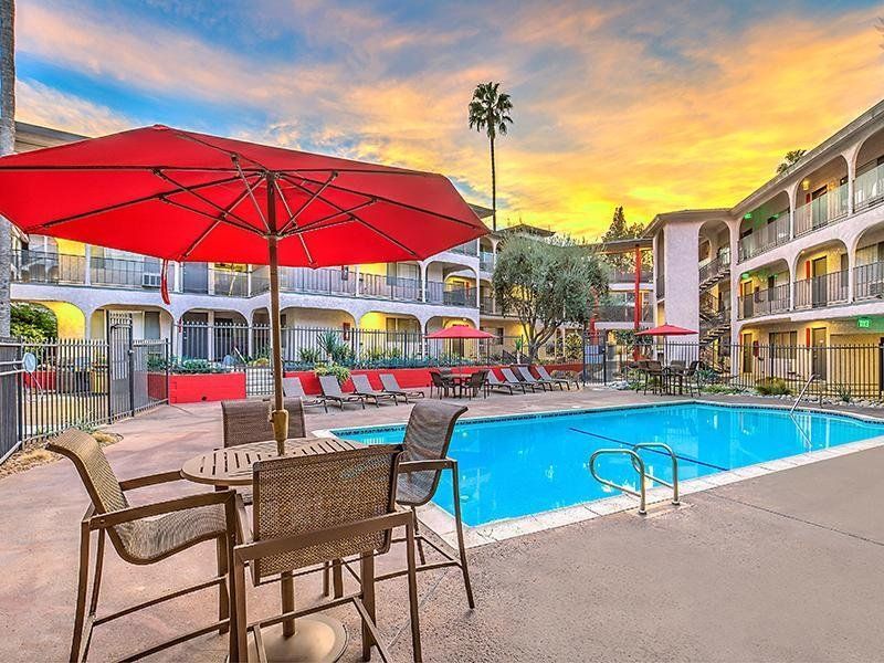 A swimming pool with a table and chairs under an umbrella.