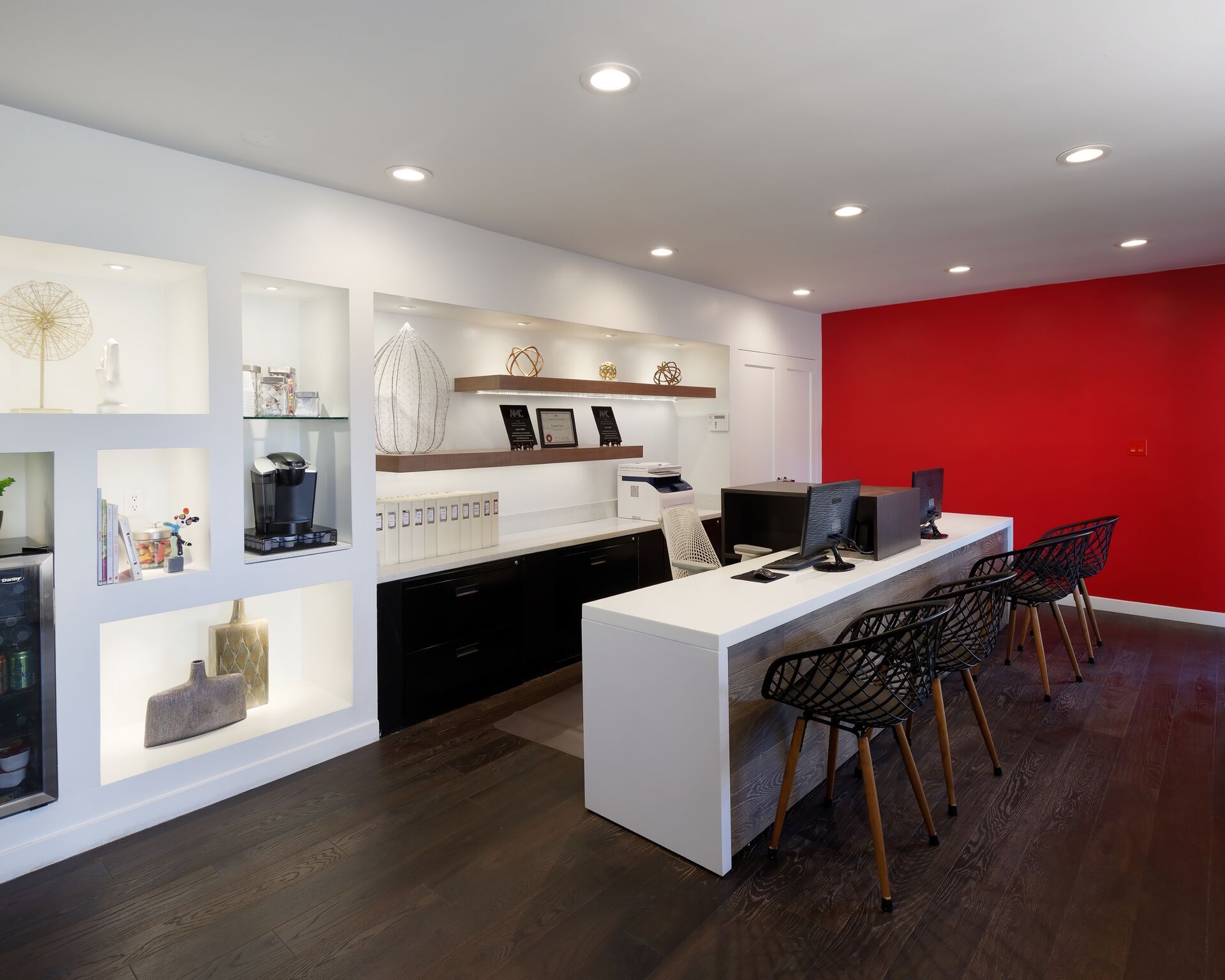 A room with a long table and chairs and a red wall