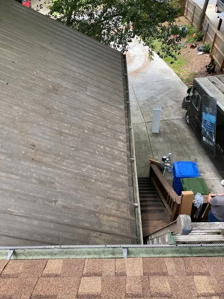View from a roof of a house with steps, a driveway, and a van parked nearby.