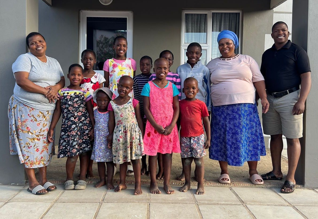 Group of people, mostly children, posing in front of a building.