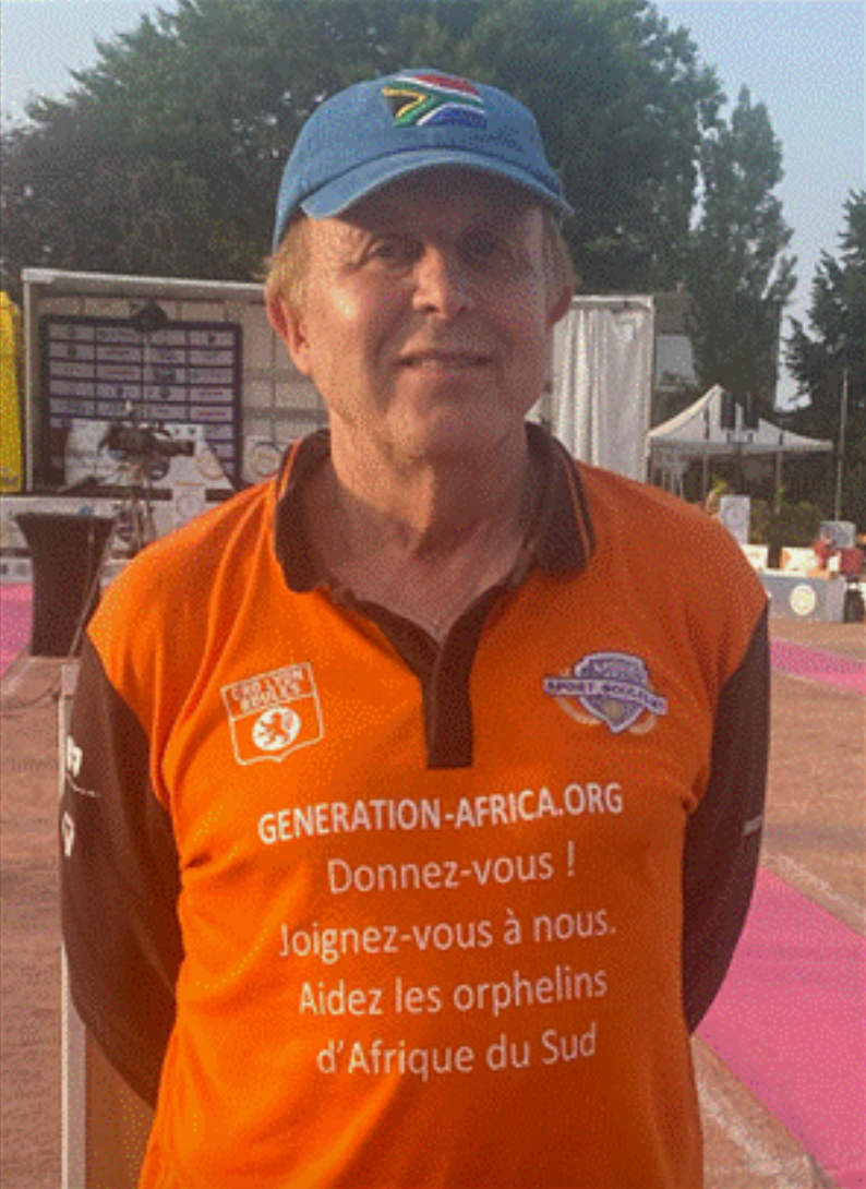 Man in orange shirt and blue cap, in outdoor setting. Shirt reads
