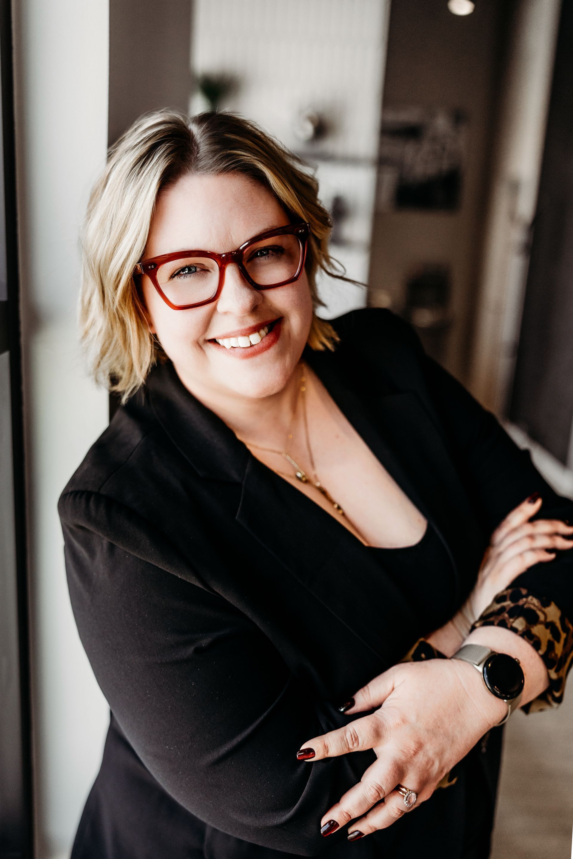 A woman wearing glasses and a black jacket is smiling for the camera.