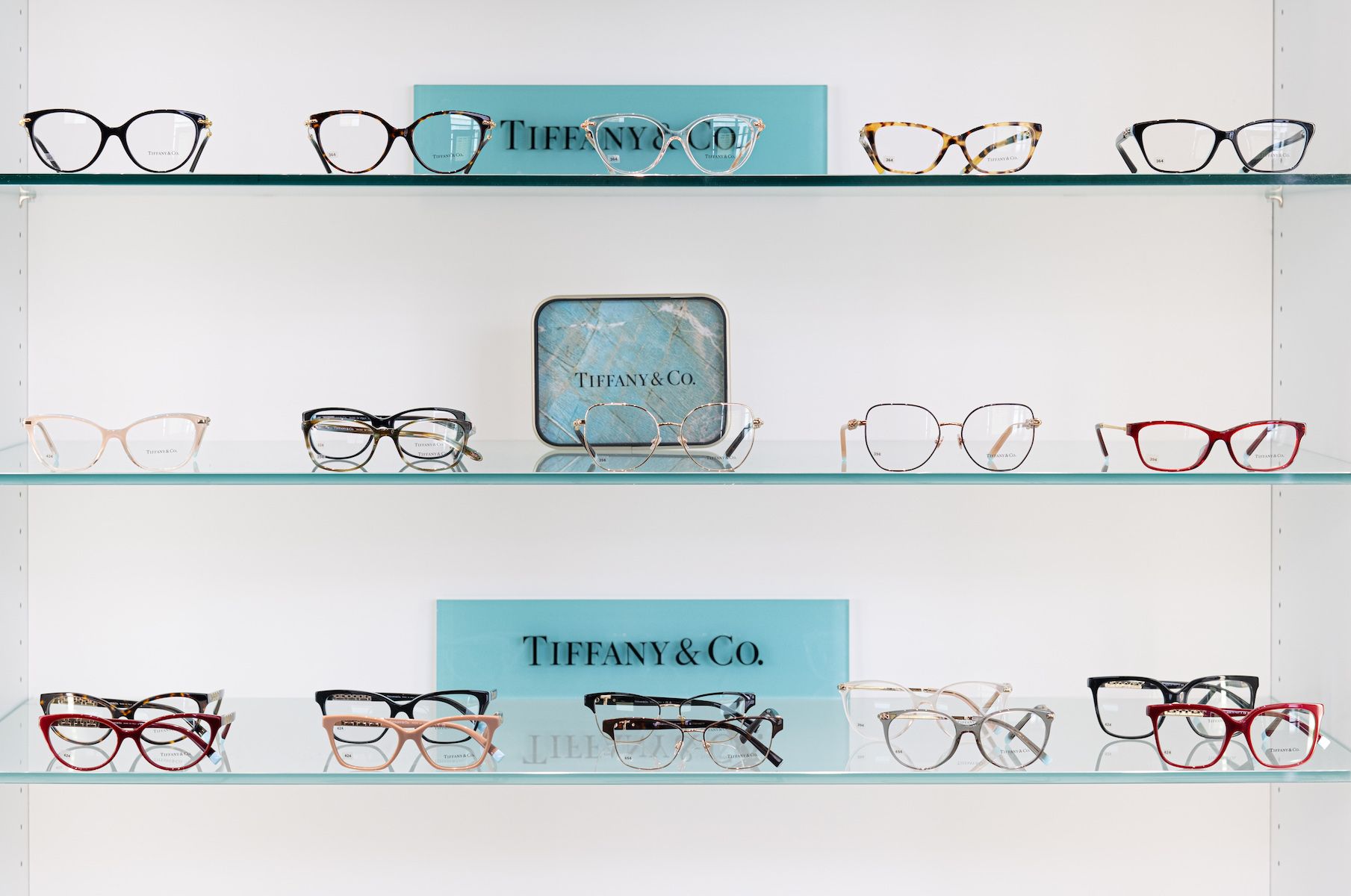 A display of tiffany and co. glasses on a glass shelf.