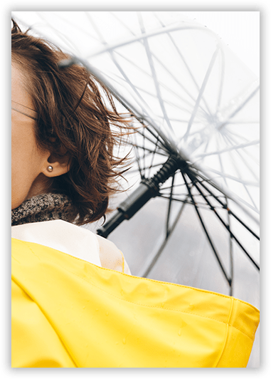 A woman in a yellow raincoat is holding an umbrella