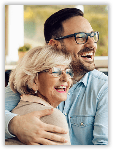 A man is hugging an older woman who is wearing glasses.