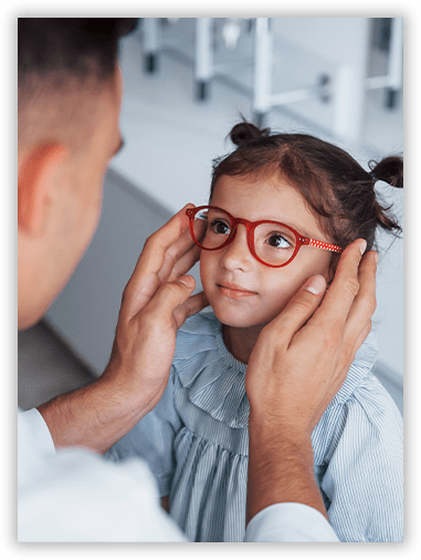 A little girl wearing glasses is being examined by an ophthalmologist.