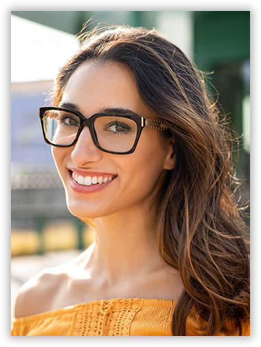 A woman wearing glasses and a yellow shirt is smiling.