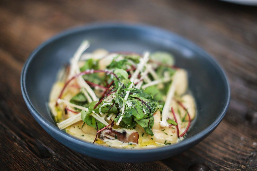 A close up of a bowl of food on a wooden table.