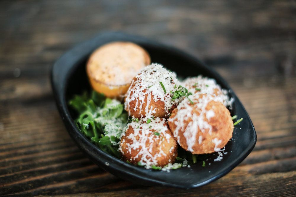 A black bowl filled with food on a wooden table.