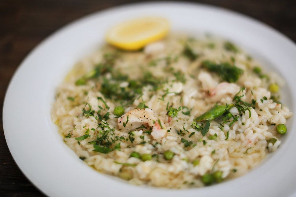 A close up of a plate of rice with shrimp and peas on a table.