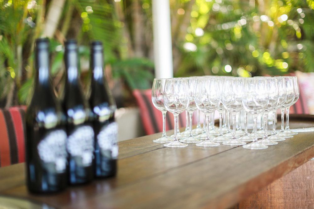A wooden table topped with bottles of wine and wine glasses.