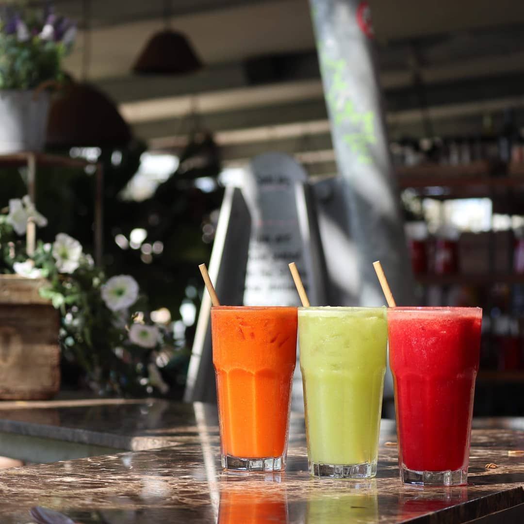 Three different colored drinks with straws on a table