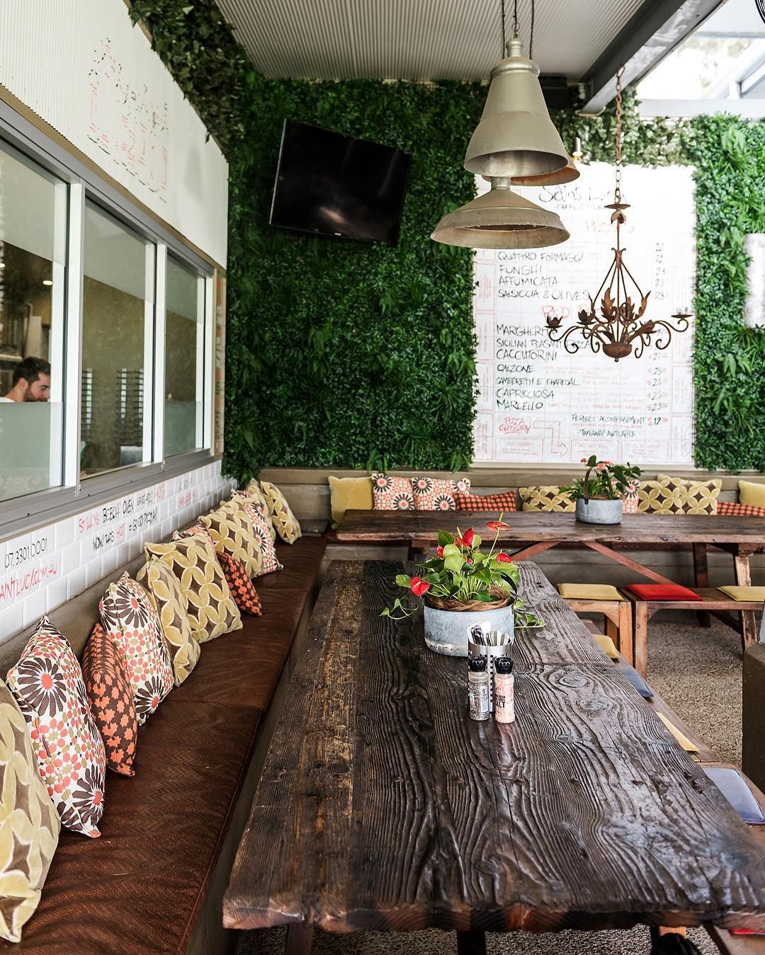 A long wooden table in a restaurant with a green wall behind it.