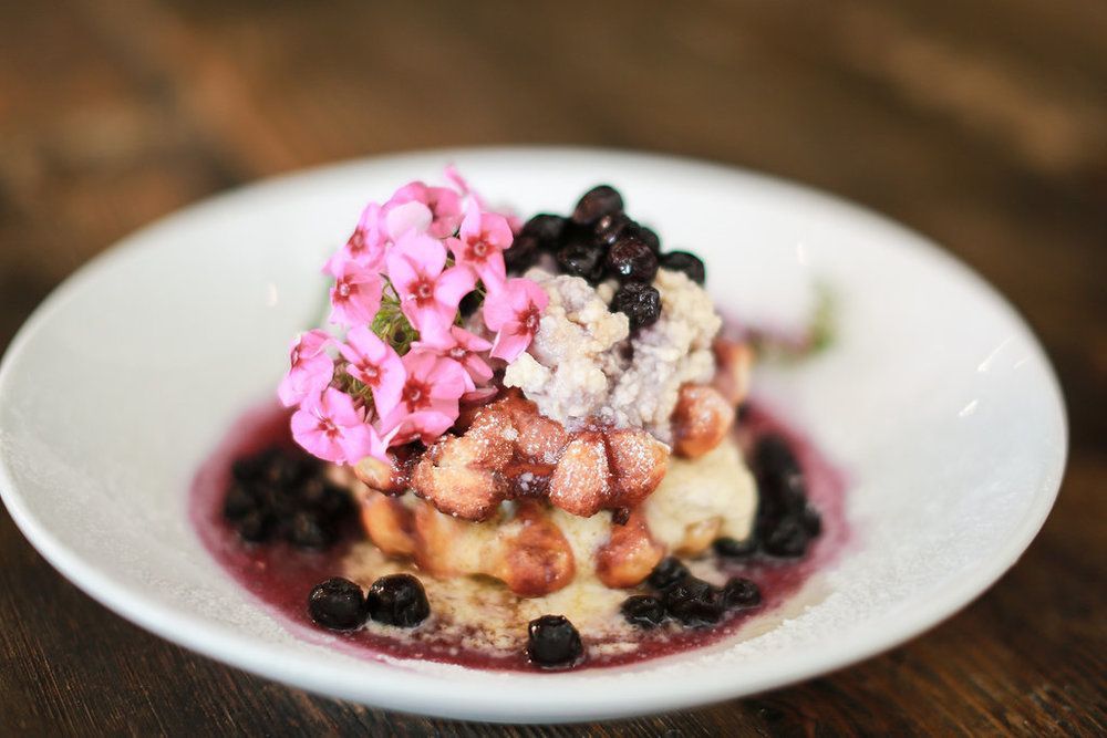 A white plate topped with a dessert with strawberries and blueberries on a wooden table.