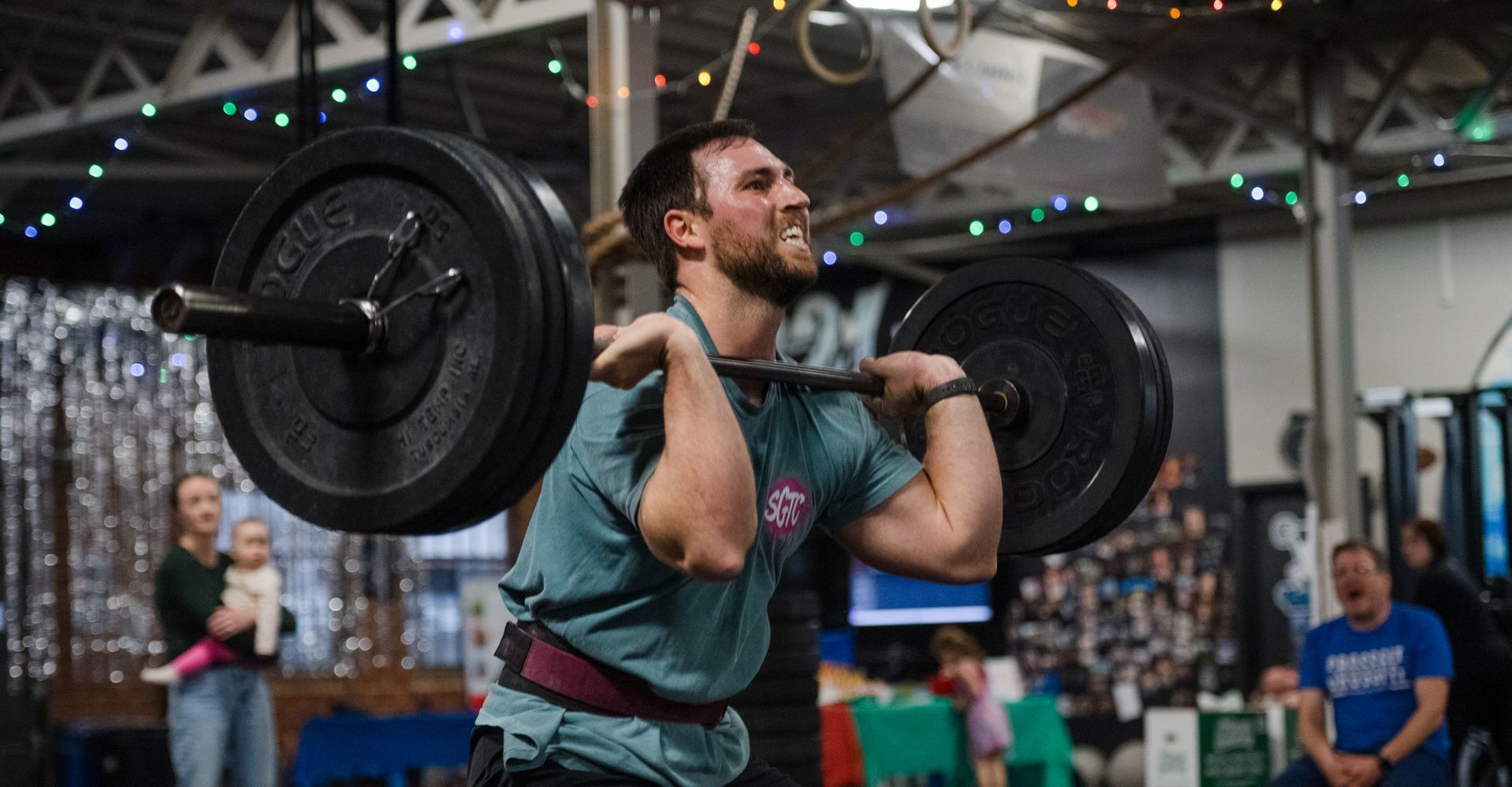 A man is lifting a barbell over his head in a gym.