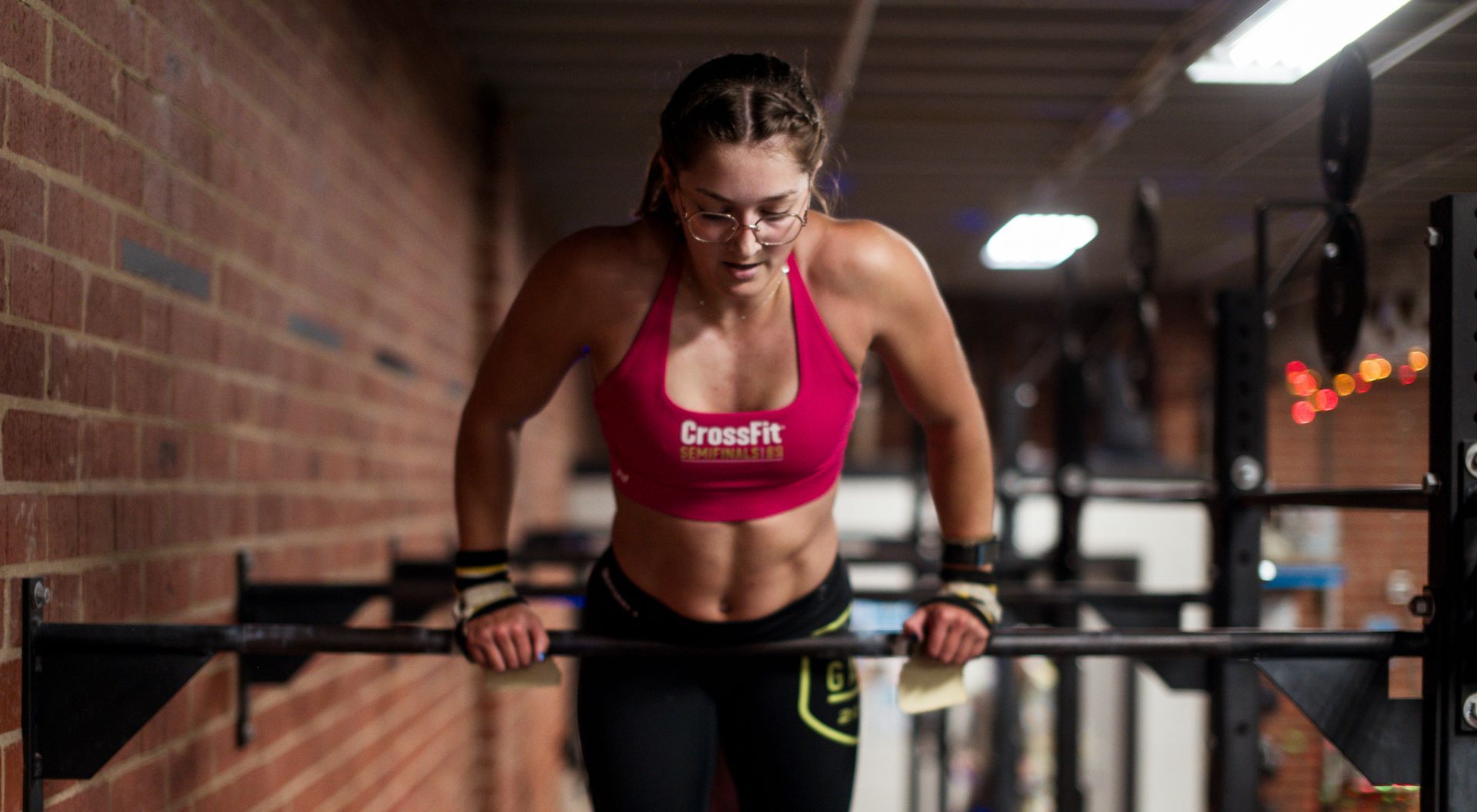 A woman is doing dips on a bar in a gym.
