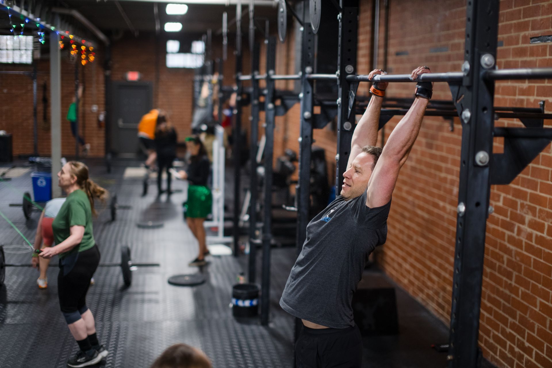 A man is doing a pull up on a bar in a gym.