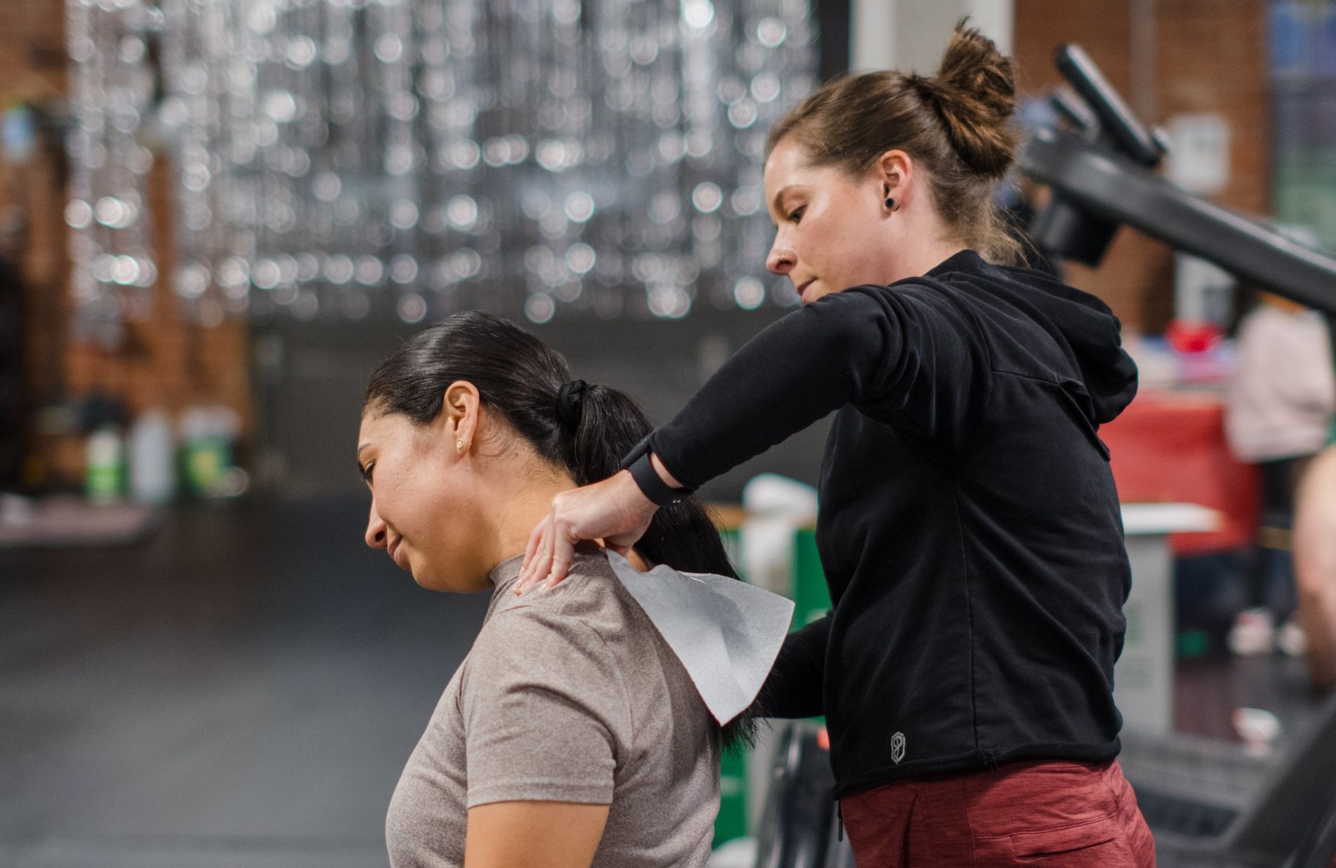 A woman is giving a massage to another woman in a gym.
