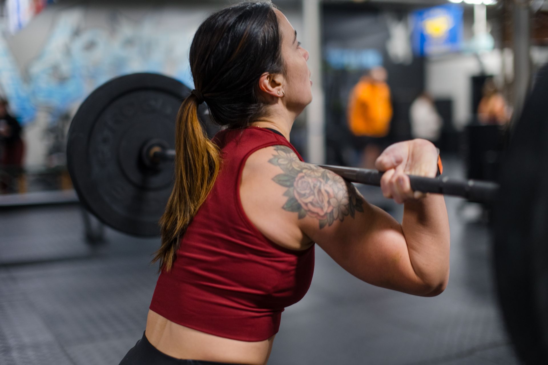 A woman is squatting with a barbell in a gym.