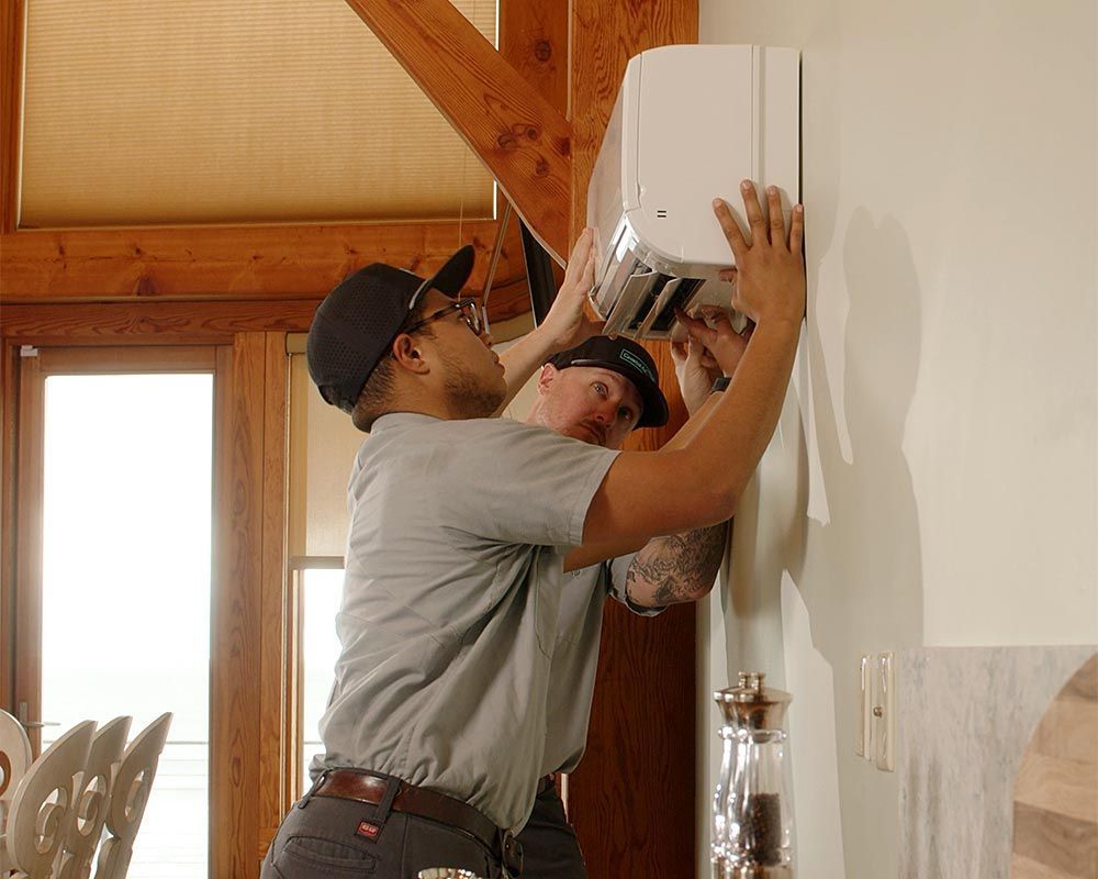 Two men are working on a wall mounted air conditioner