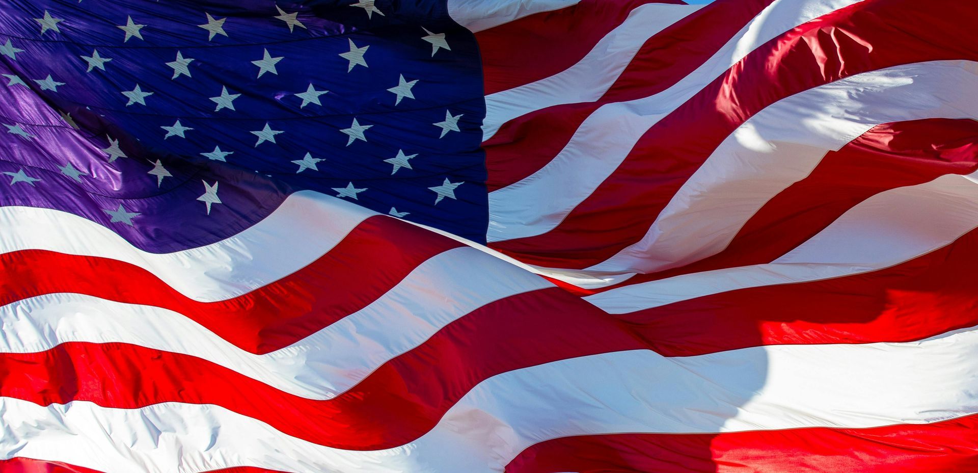 Waving American flag with red and white stripes and white stars on a blue field